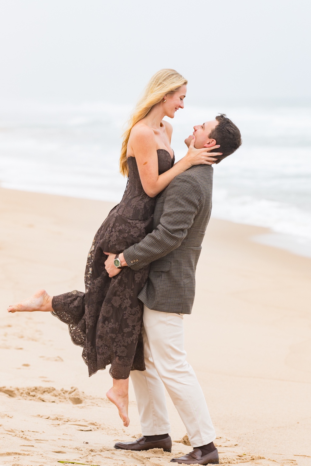 Bryce lifting Lily on the beach, the two smiling at each other