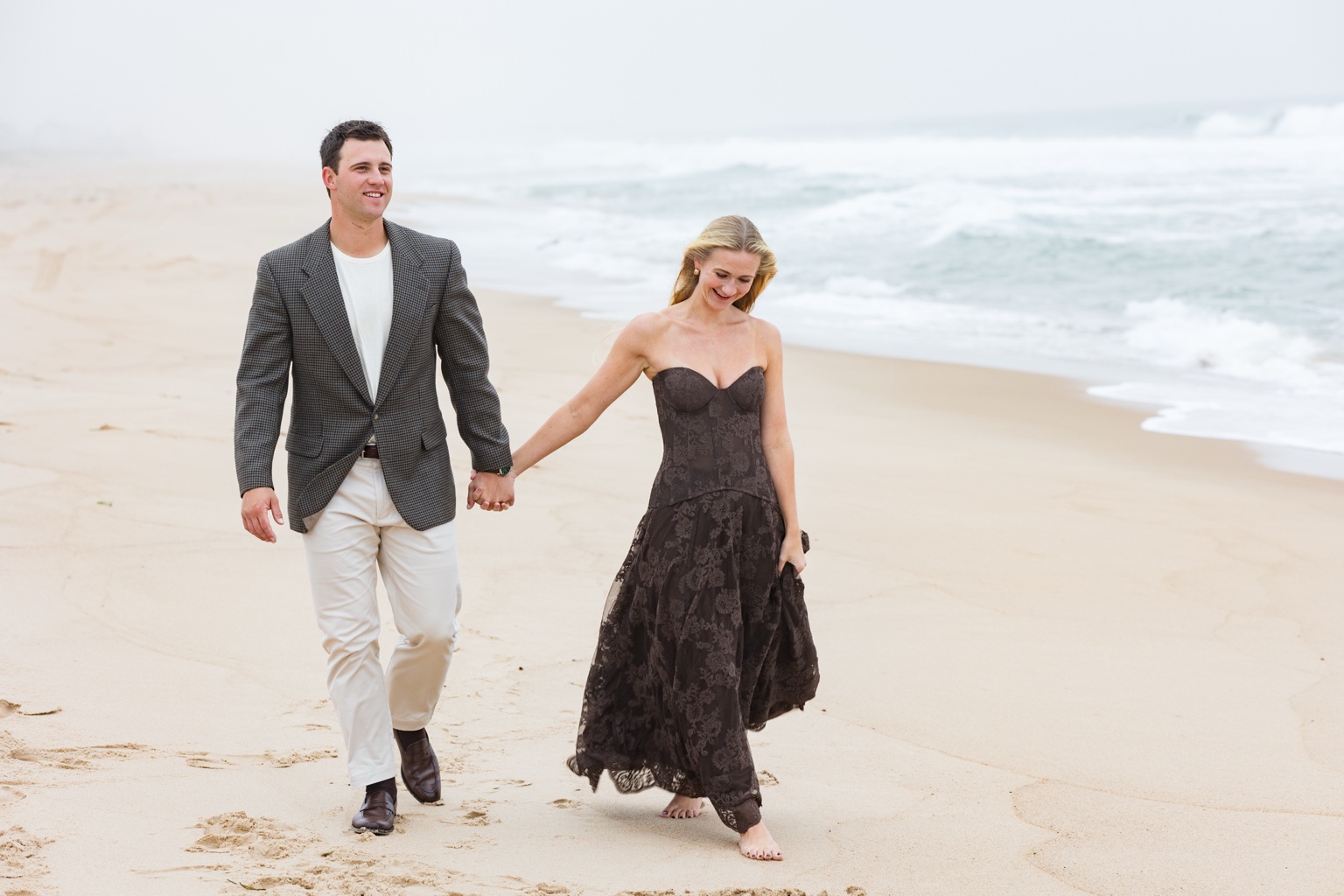 Lily and Bryce walking hand in hand along the shoreline